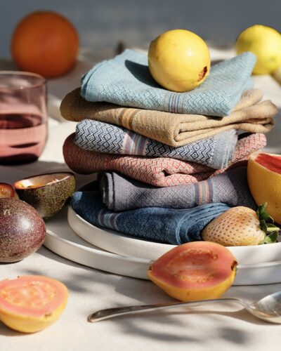 A colourful alfresco table set with crockery, glasses, fresh fruit and Mungo Boma Napkins