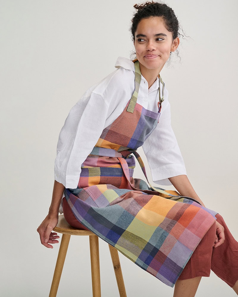Model sitting on stool in the Alles Apron and a white linen shirt.